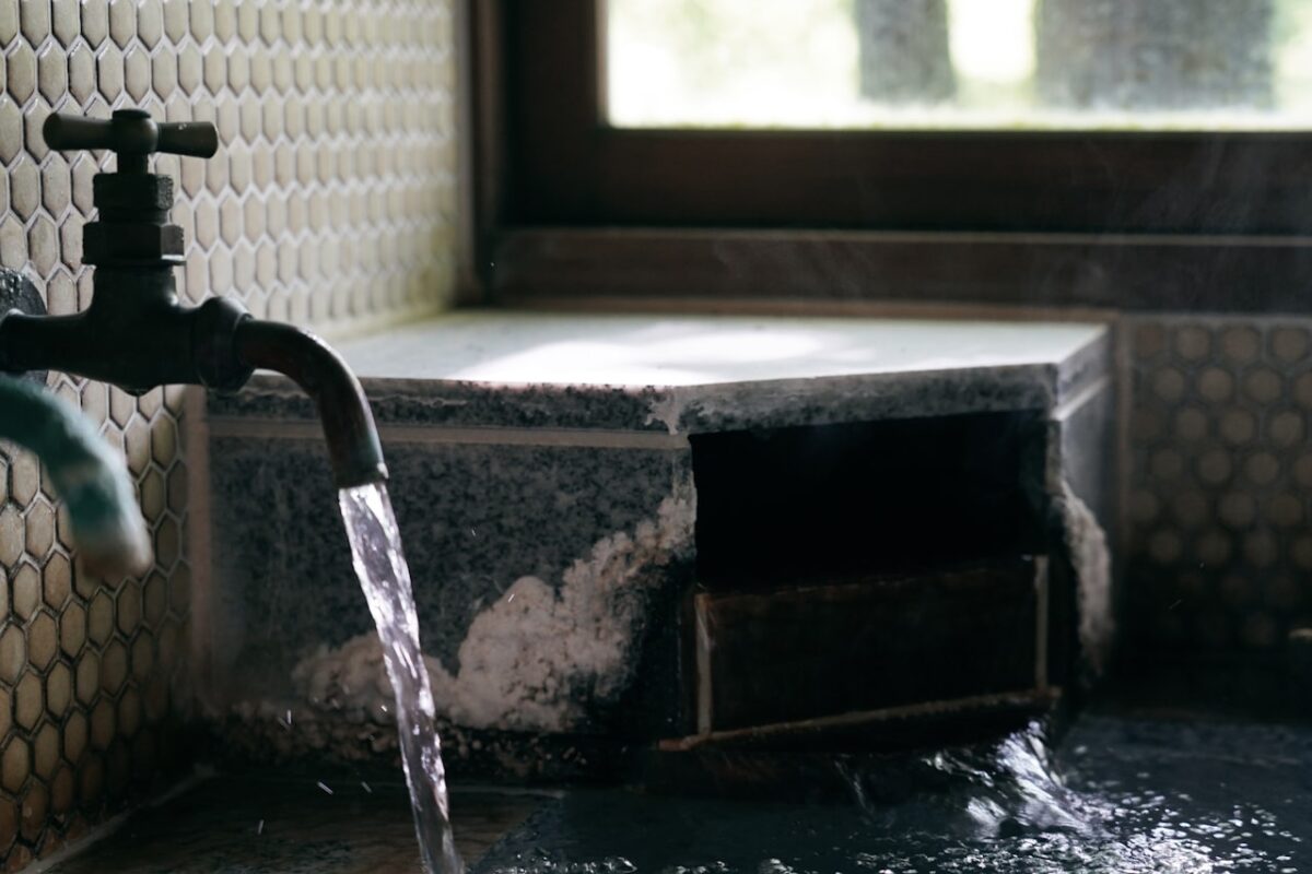 A bath faucet with water running beside a window in Japan