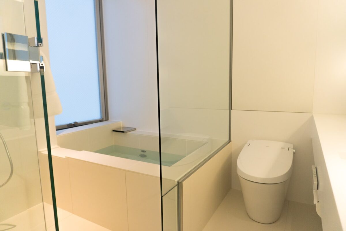 A clean Japanese bathroom with a toilet and glass shower