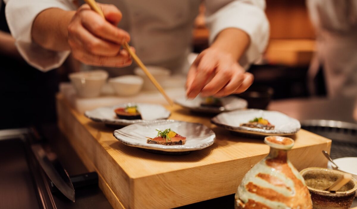 A person holding chopsticks over a plate of Japanese food