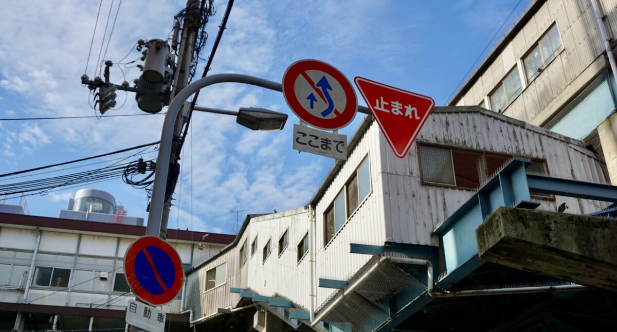 Will English Get You By in Japan? Where It Works — and Where a Little Japanese Helps A red and blue street sign on the side of a road in Japan