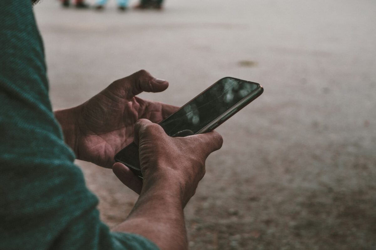 Close-up of hands holding a smartphone outdoors