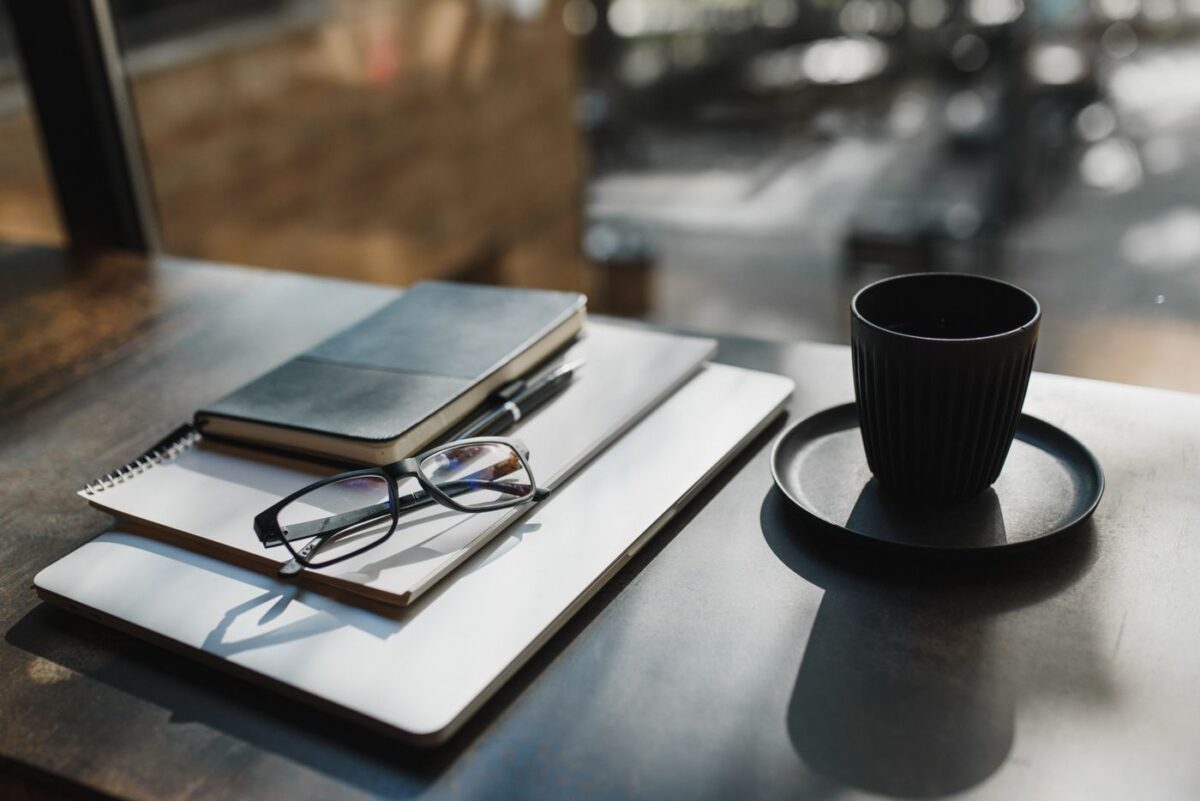Private Japanese Lessons in London: Online Classes, with In-Person Café Sessions Available Glasses, notebook and a cup of black coffee on a tidy desk