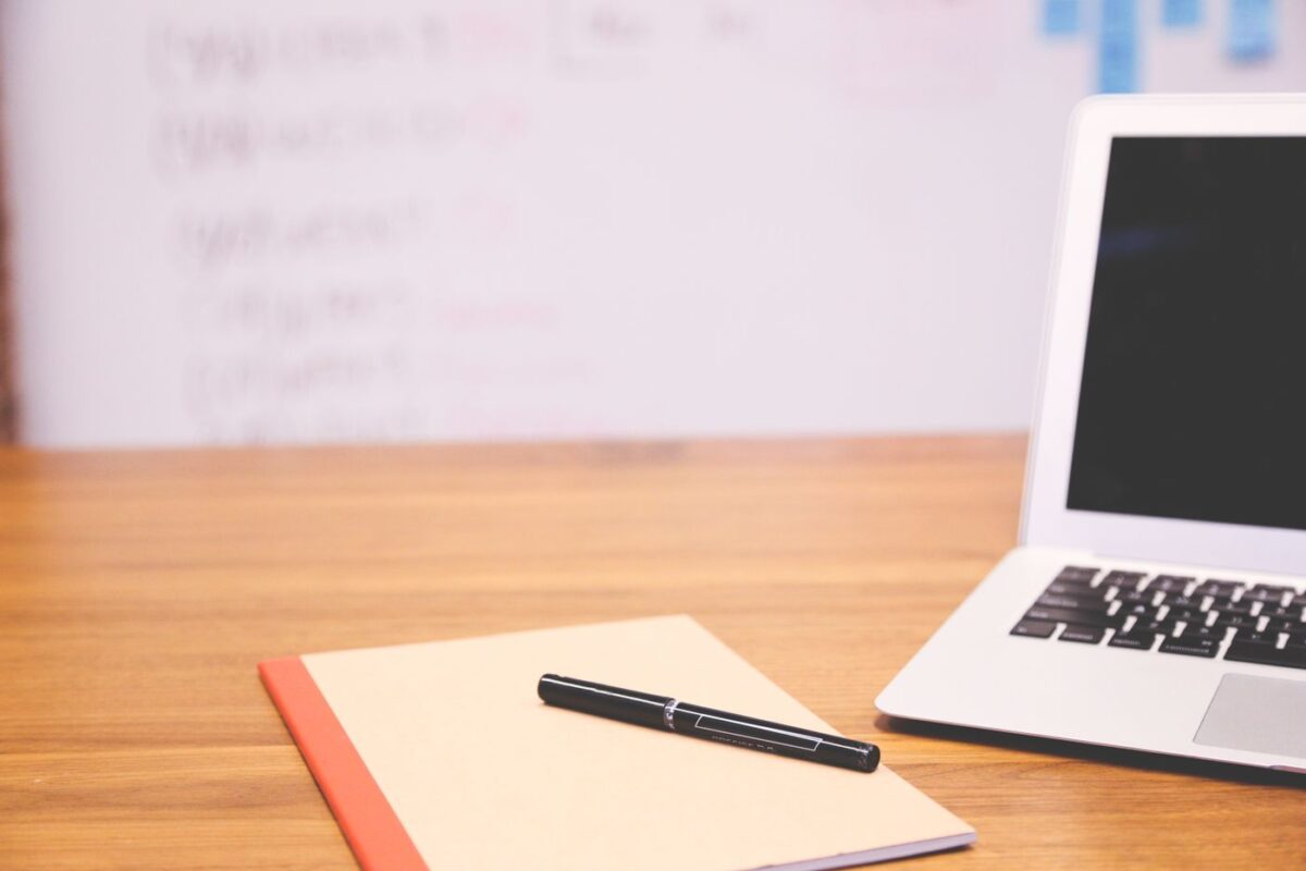 Laptop, notebook and pen on a wooden desk